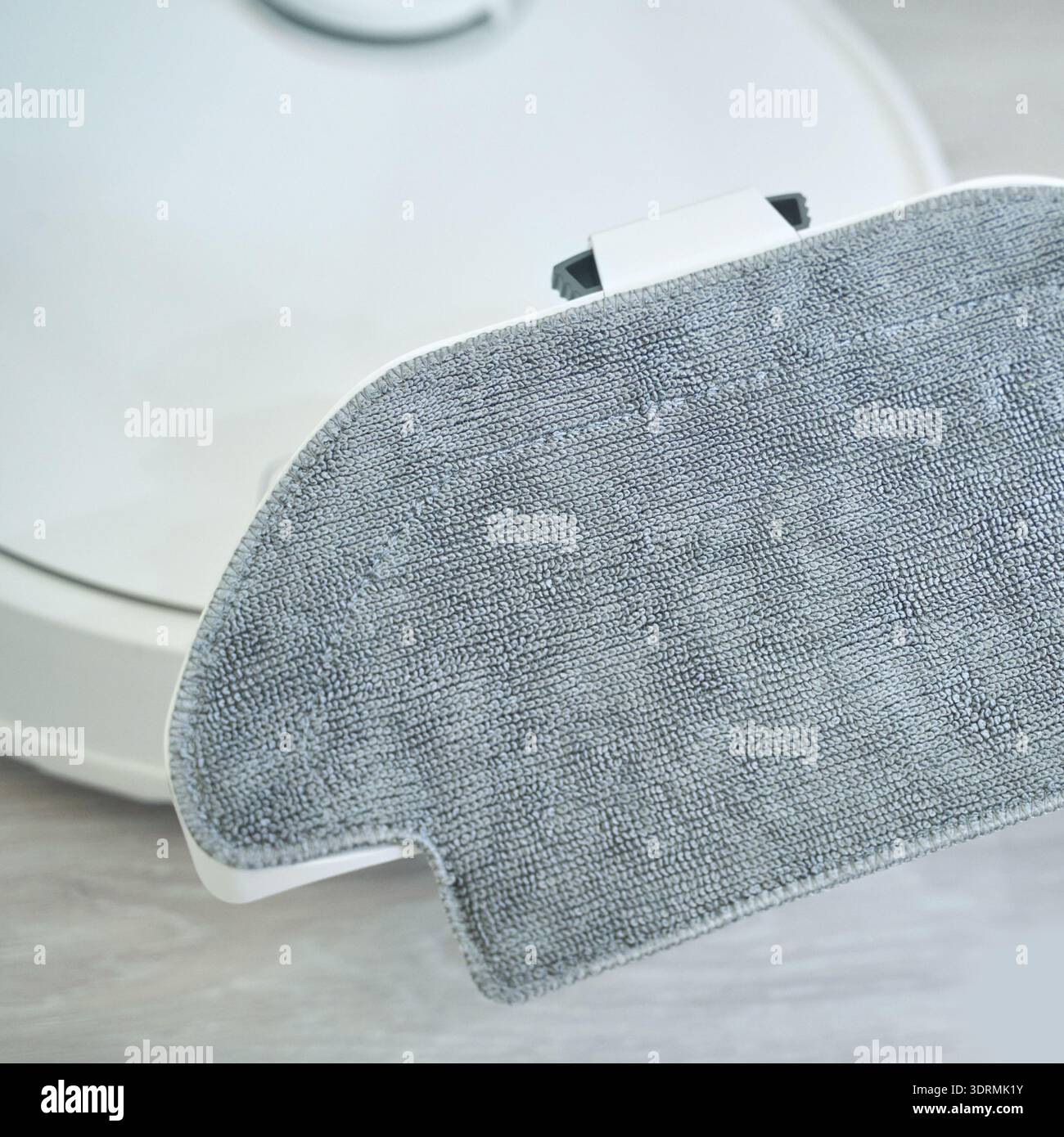 Hand holding robotic vacuum mop attachment for efficient home cleaning on light Stock Photo