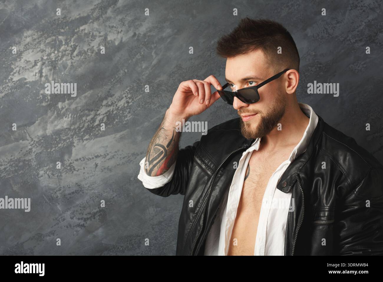 Man Poses Confidently in a Black Leather Jacket and Sunglasses Against ...