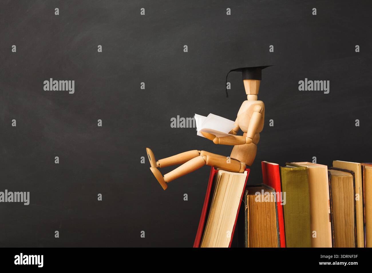 Graduation Figure Reading on Top of Stacked Books in a Study Setting ...