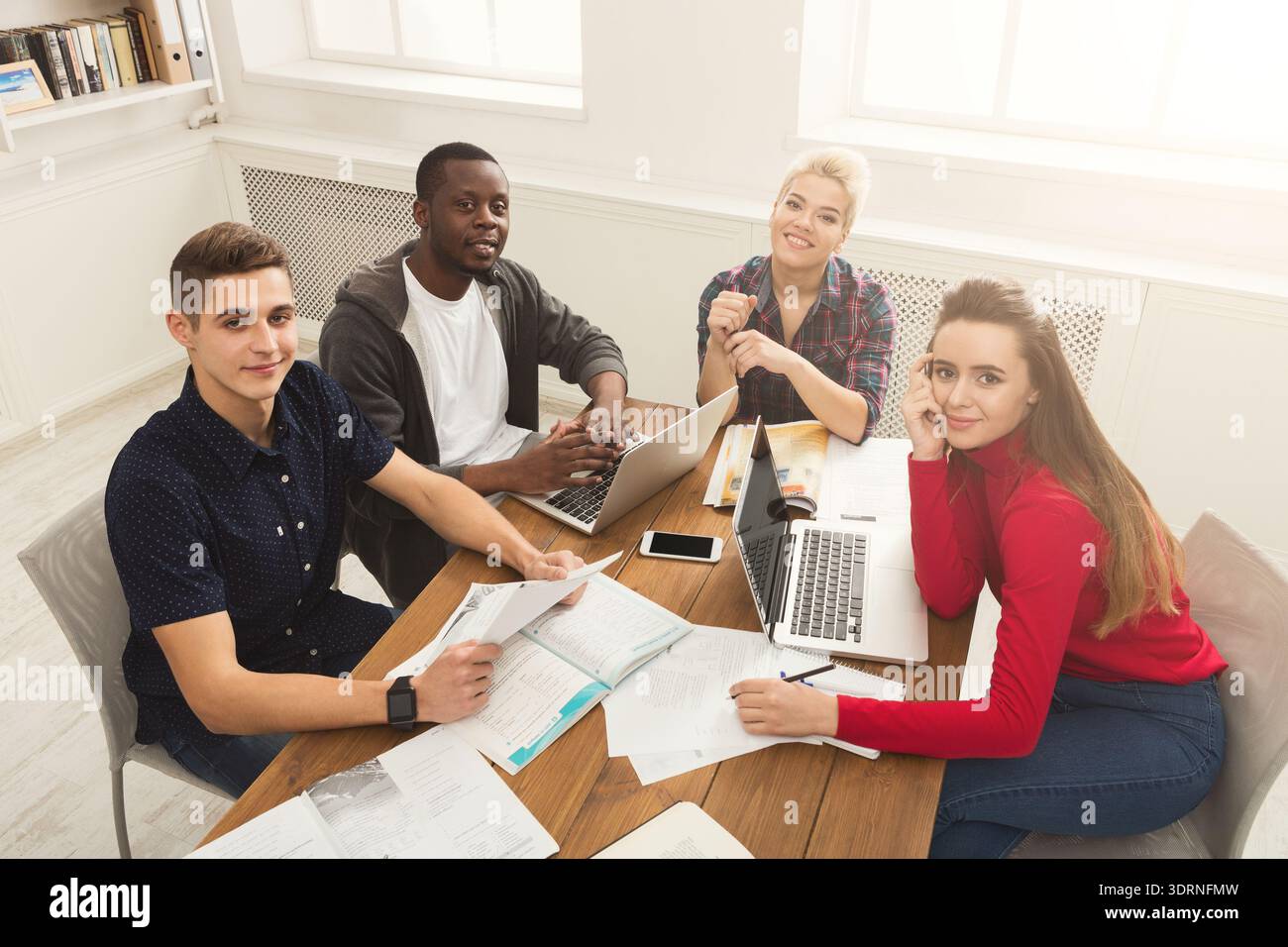 Group of Students Working Together on Projects at a Study Table in a Bright Room Stock Photo