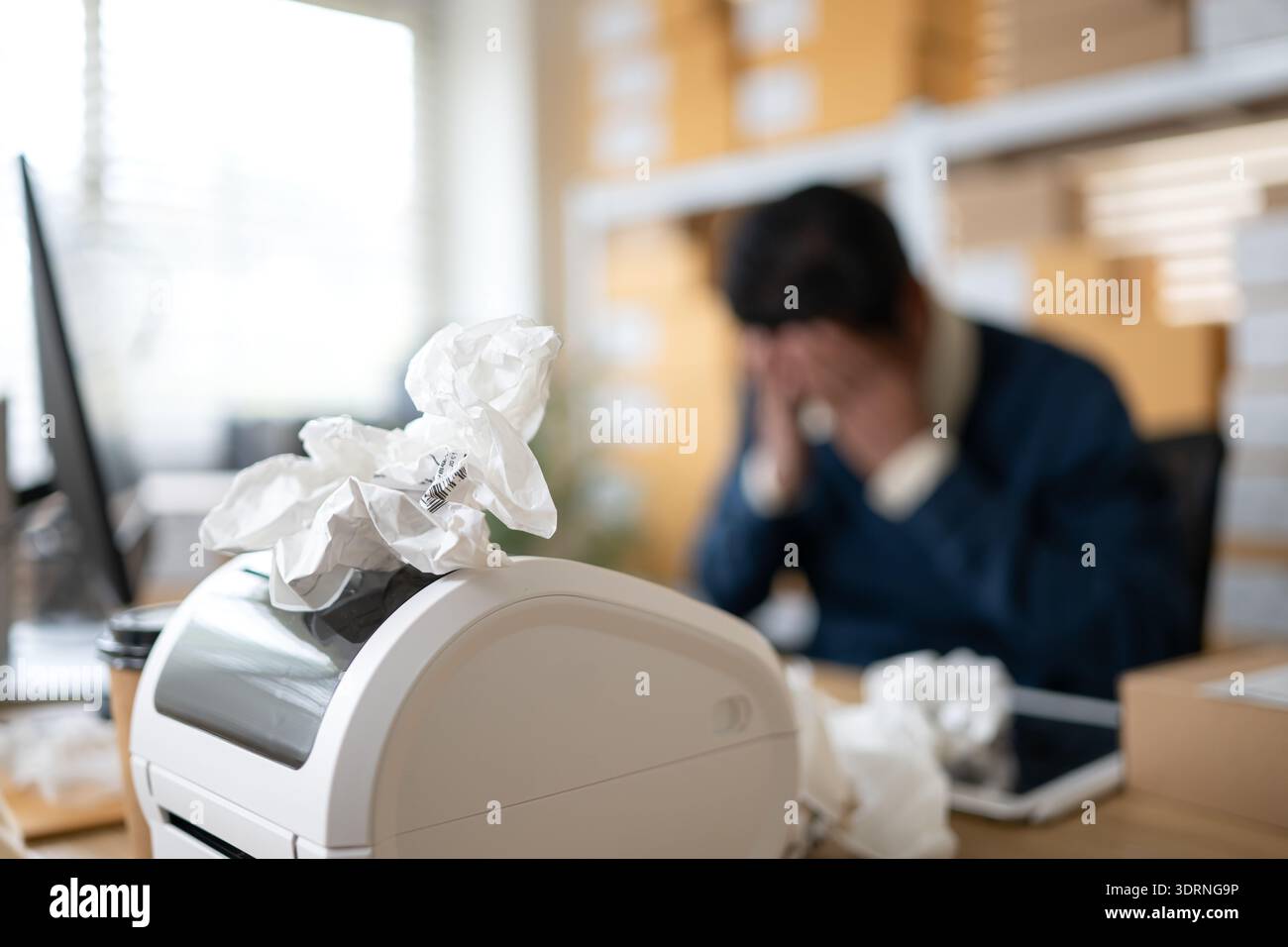 Label printer malfunction on work desk while stressed warehouse owner faces business problems Stock Photo