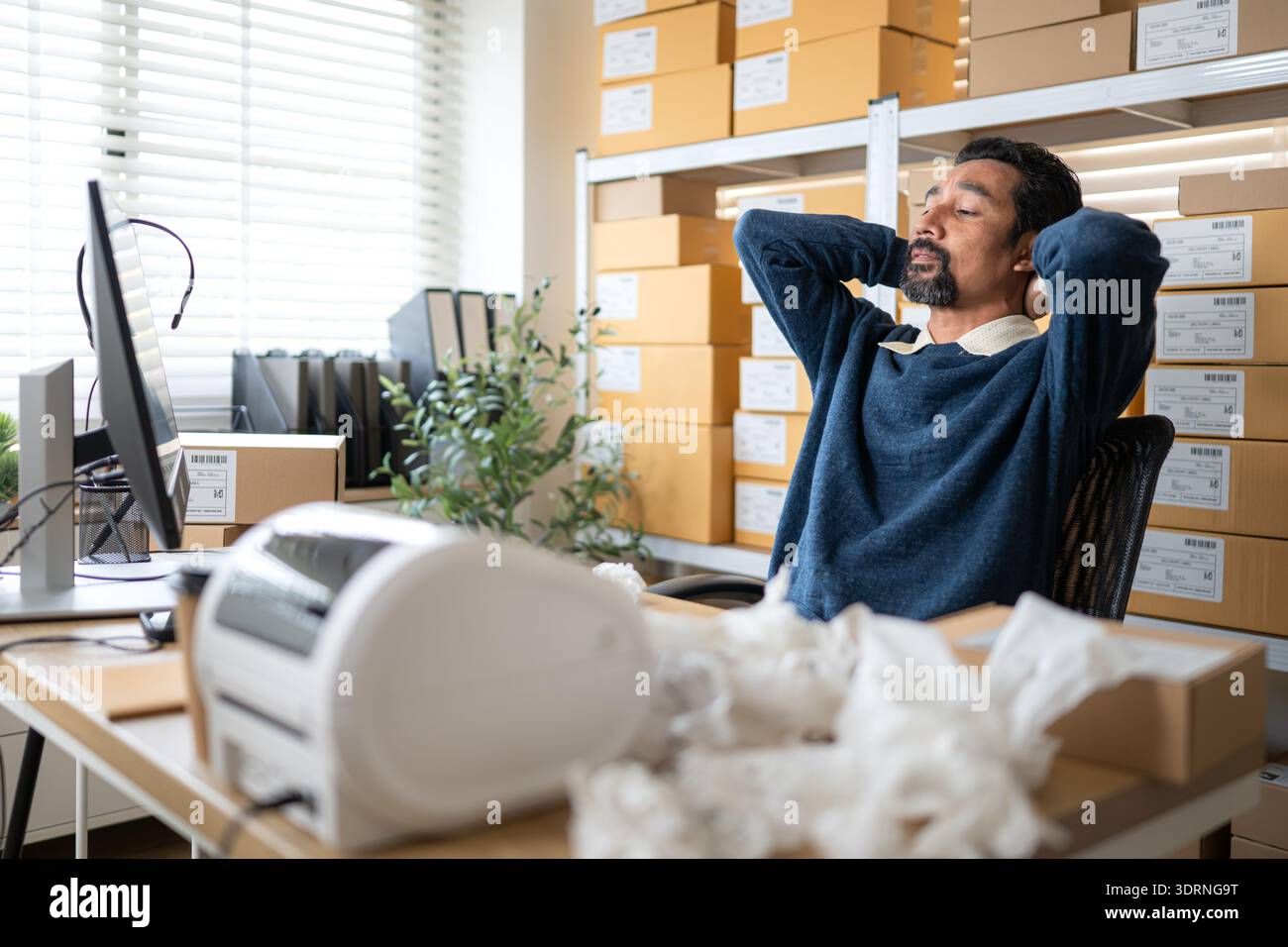 Label printer malfunction on work desk while stressed warehouse owner faces business problems Stock Photo