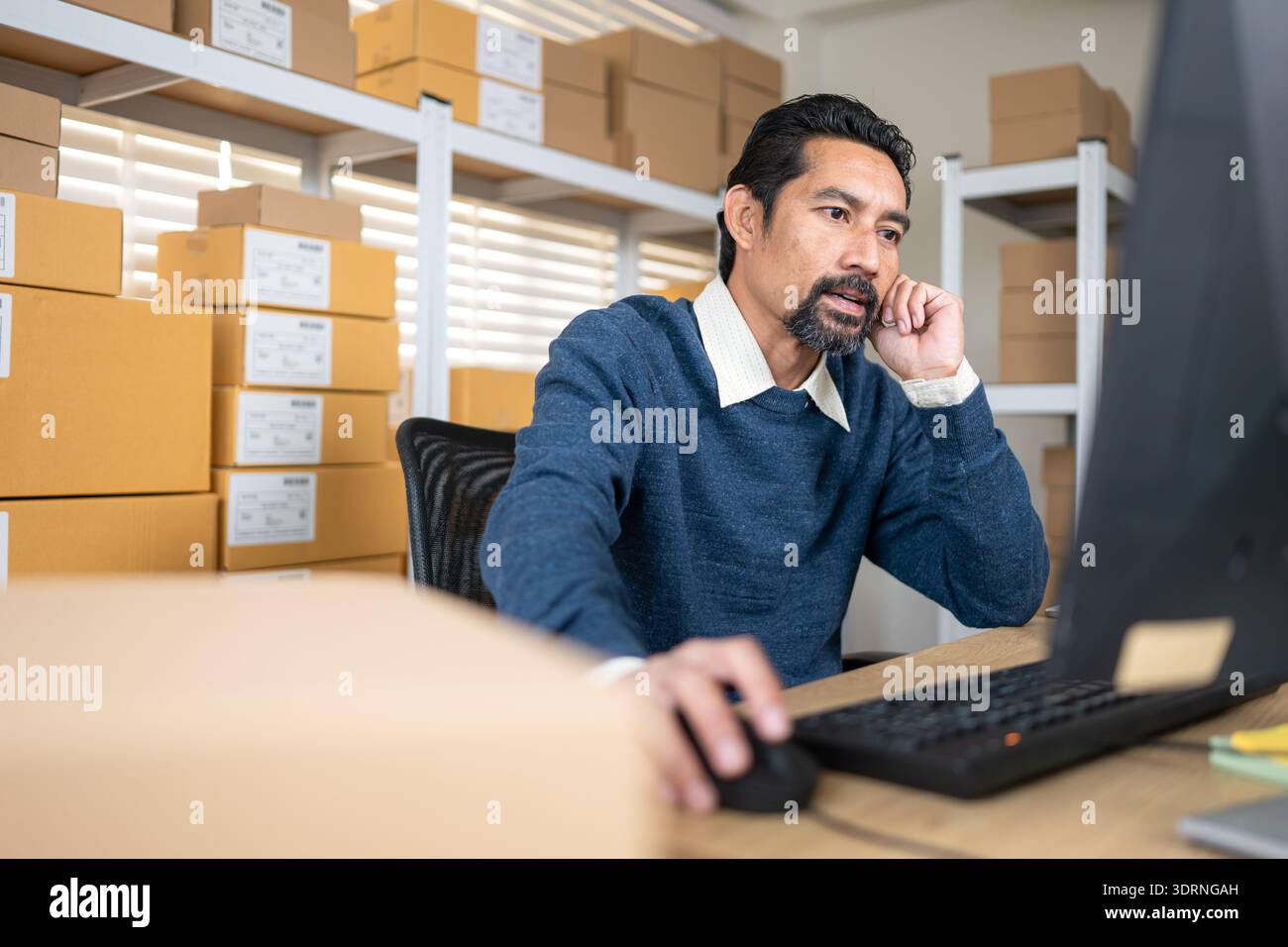 Warehouse manager analyzing data on desktop computer, planning inventory and business operations Stock Photo