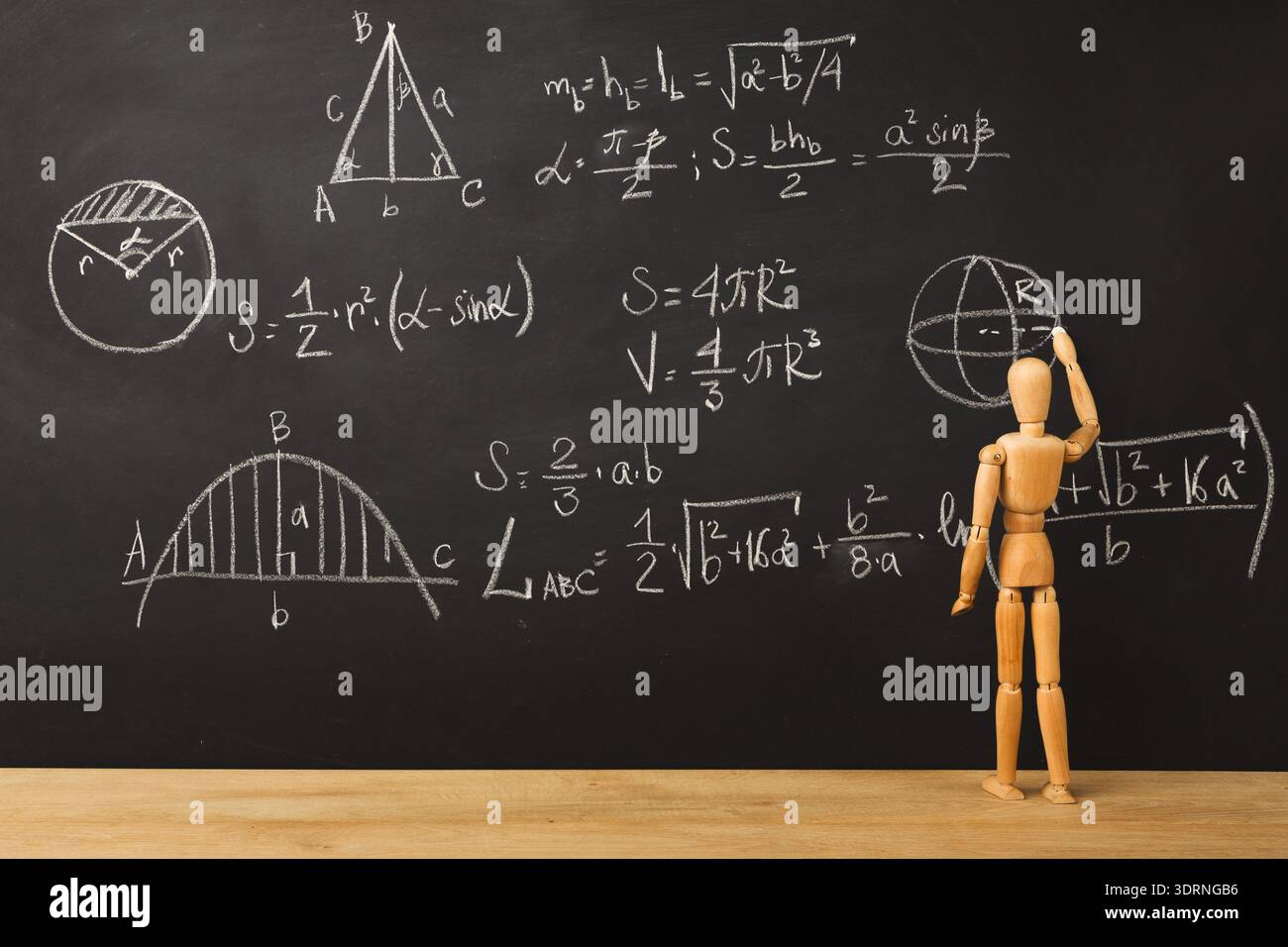 Math Concepts and Drawings on a Blackboard With a Wooden Figure Writing Equations Stock Photo