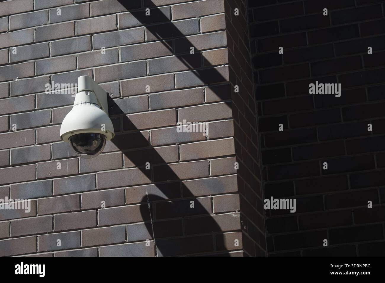 Security camera mounted on a brick wall in daylight Stock Photo