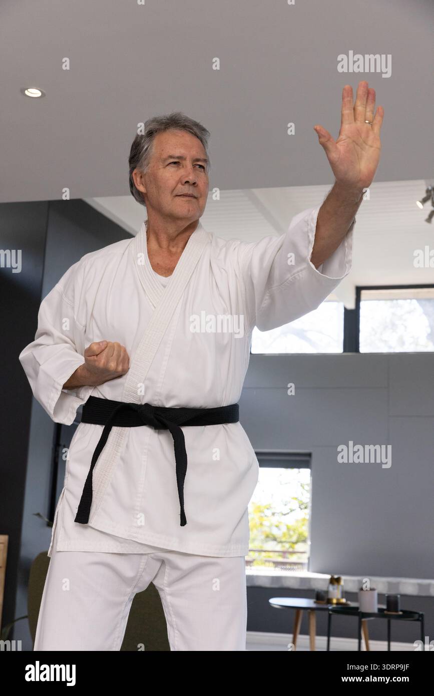 Senior male in white karate gi and black belt demonstrating block ...