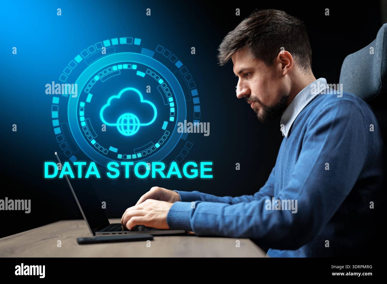 Man sits at desk using laptop for data storage tasks in modern workspace setting Stock Photo