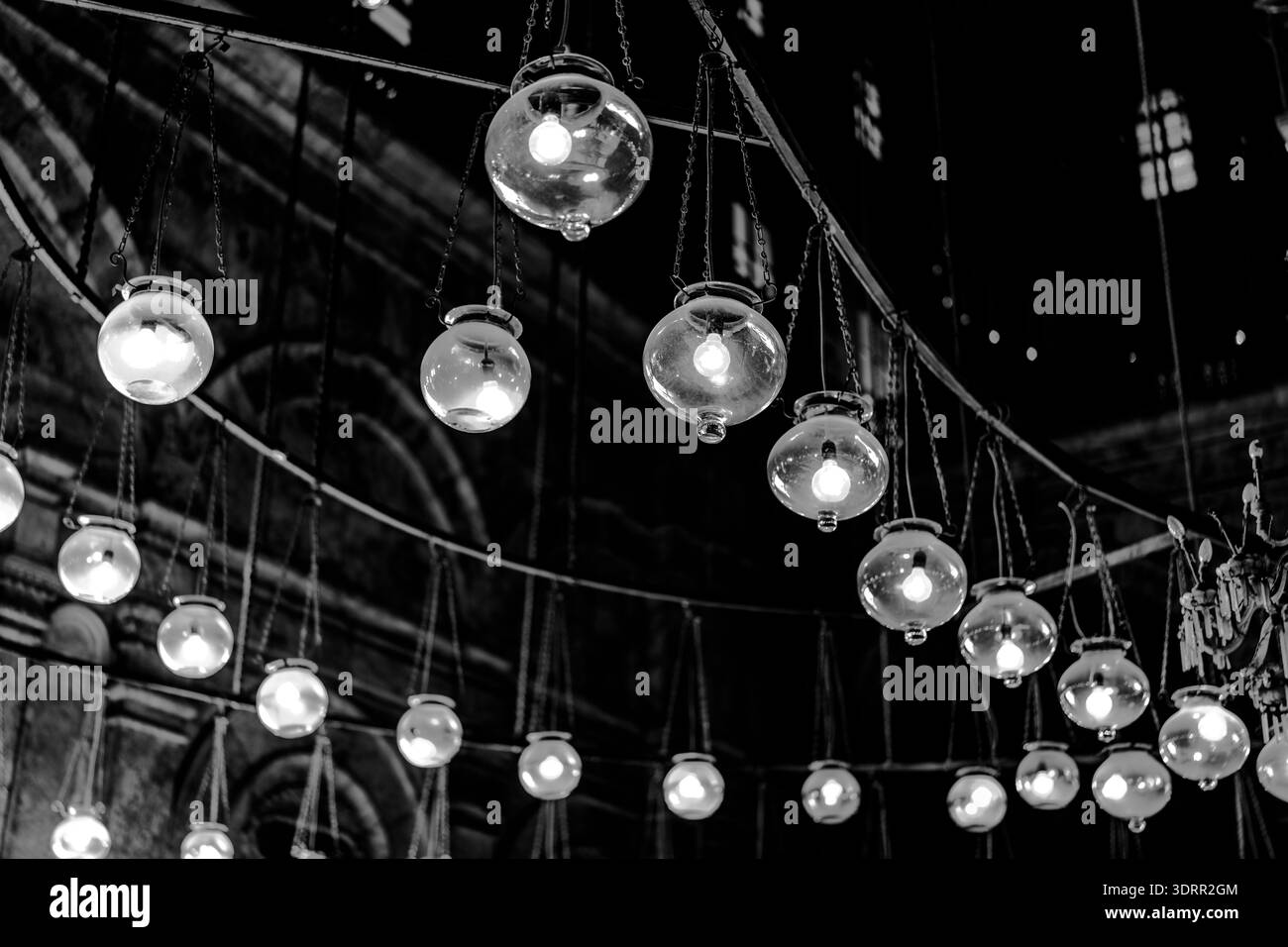 Black and white view of suspended glass lamps illuminating historic stone architecture in Giza, Egypt, emphasizing symmetry, contrast, and timeless in Stock Photo