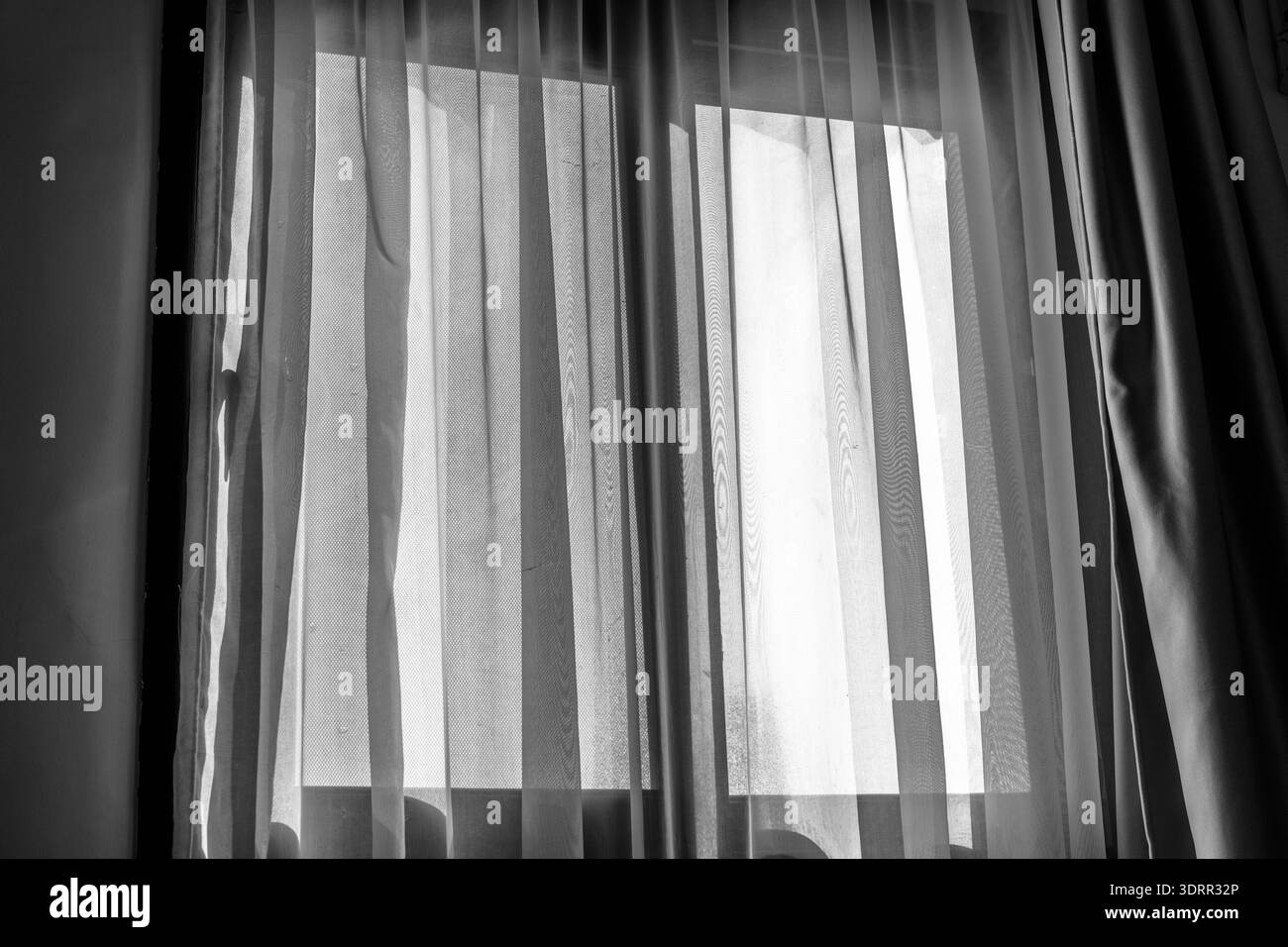 Black and white view of soft daylight passing through curtains at a window in Giza, Egypt, emphasizing contrast, stillness, and intimate interior atmo Stock Photo