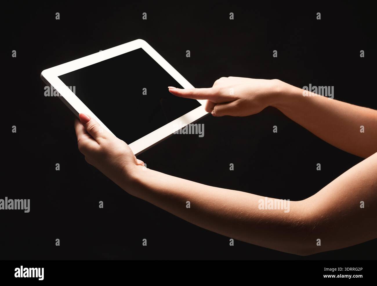 Hand Interacts With a Blank Tablet Screen in a Dark Setting With Focus on Technology Use Stock Photo