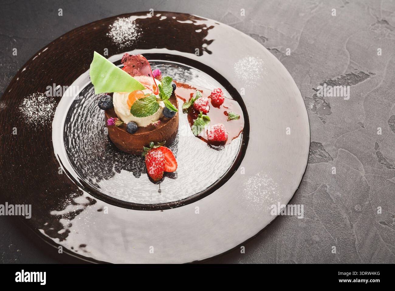 Collection of Delicious Desserts With Fruits and Sauces on a Black Plate Stock Photo