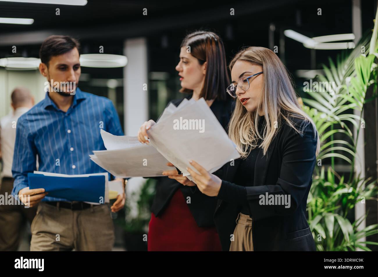 Business team reviews documents in a modern office during a collaborative work session Stock Photo