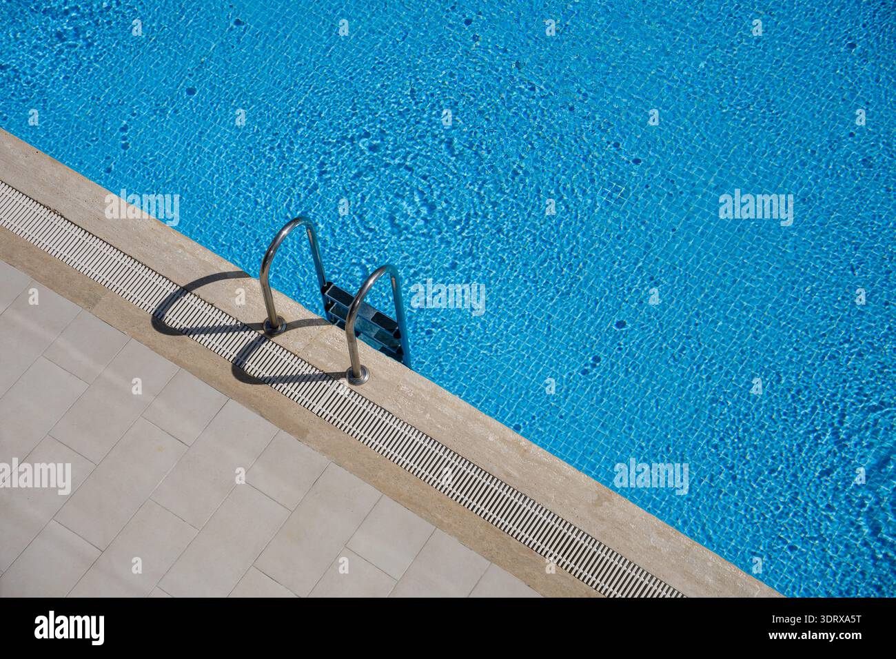 Aerial view of empty swimming pool with steps, handrails and blue water ...