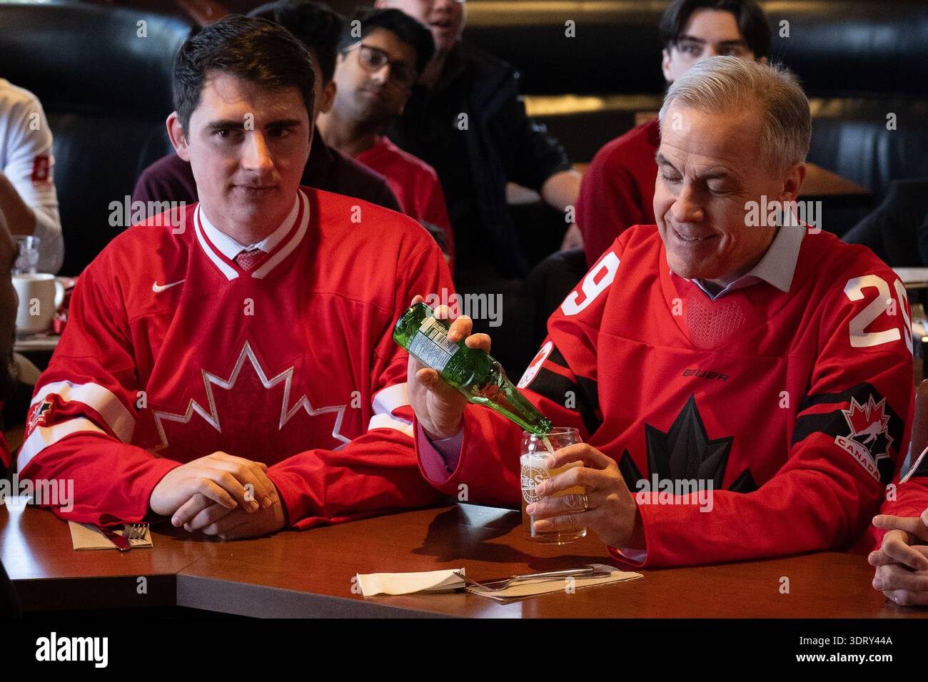 Prime Minister Mark Carney pours himself a beverage while watching an ...