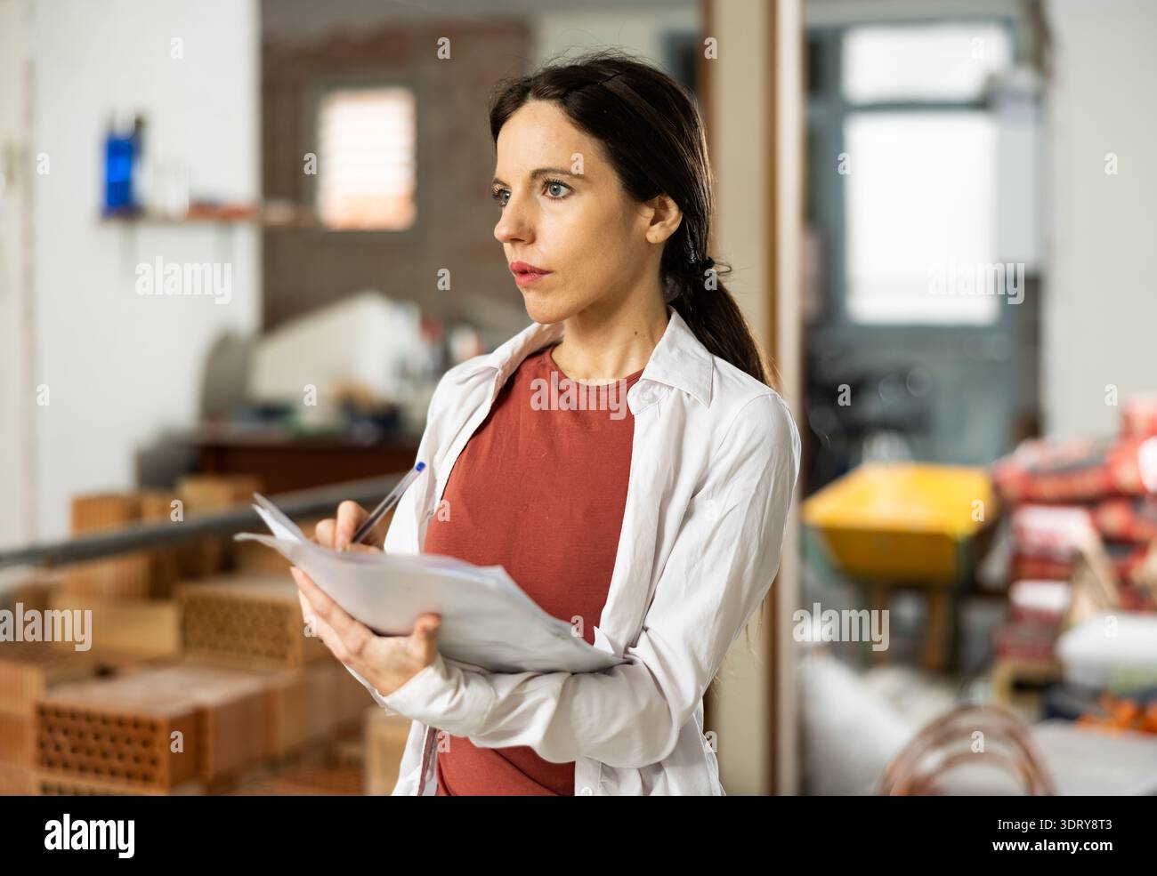 Interested brunette making notes while planning home renovation Stock Photo