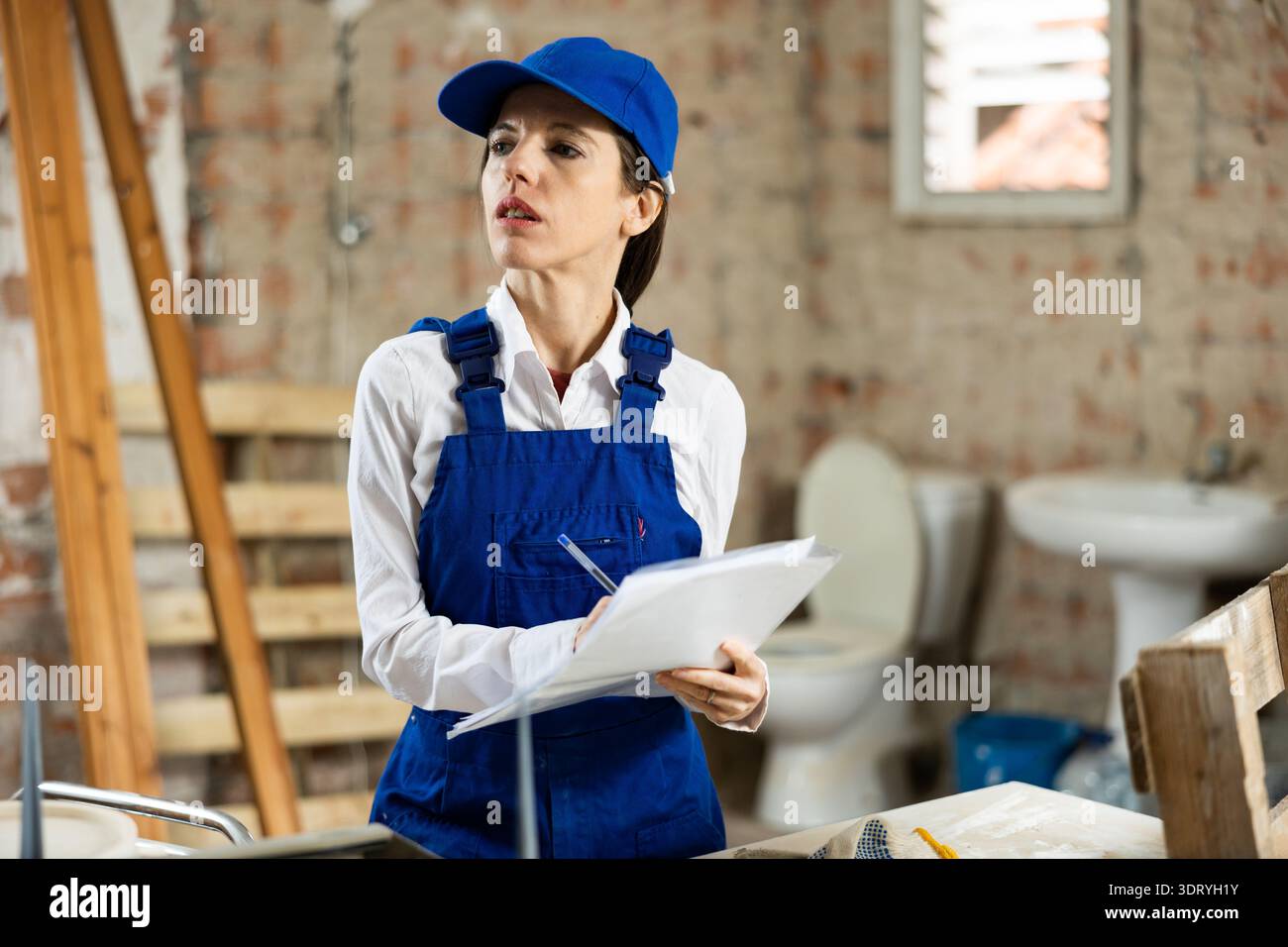 Female designer making checklist while planning building overhaul Stock Photo