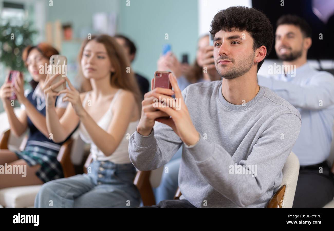 Young guy using mobile phone to scan QR code during interactive lesson Stock Photo