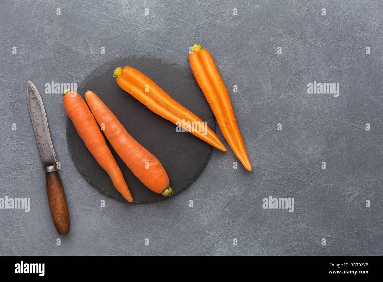 Fresh Carrots and Knife on Dark Surface Ready for Preparation in Kitchen Setting Stock Photo