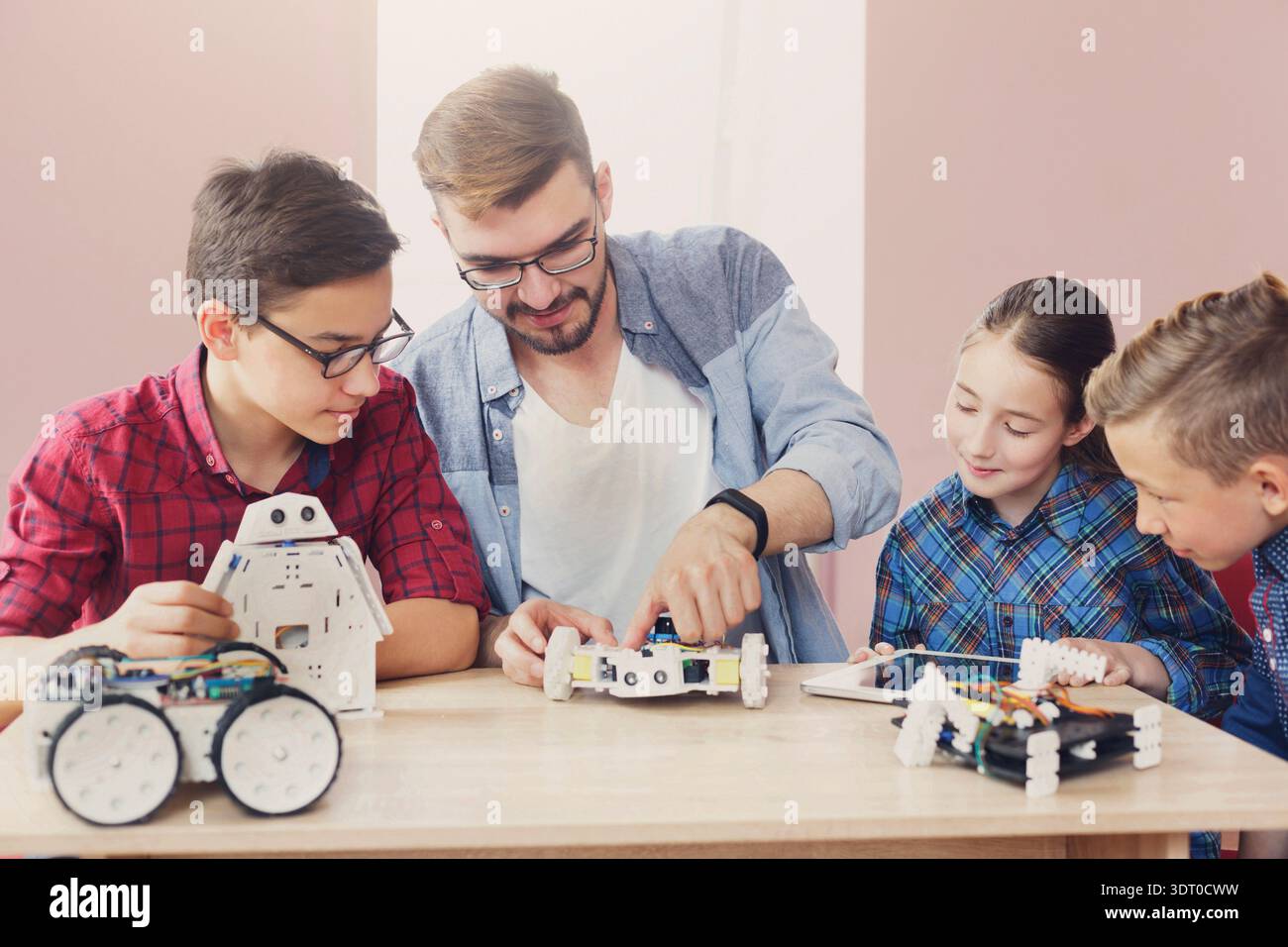 Kids Learn Robotics With a Teacher While Building Projects in a Classroom Setting Stock Photo