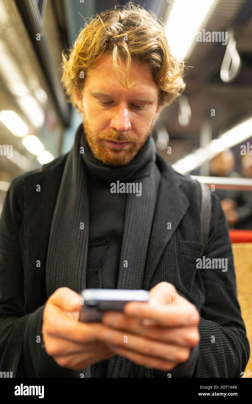 Red haired man commuting using smartphone in subway Stock Photo