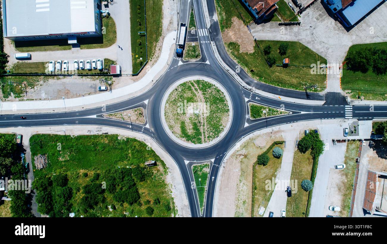 Aerial view of a roundabout intersecting roads amidst green spaces and ...