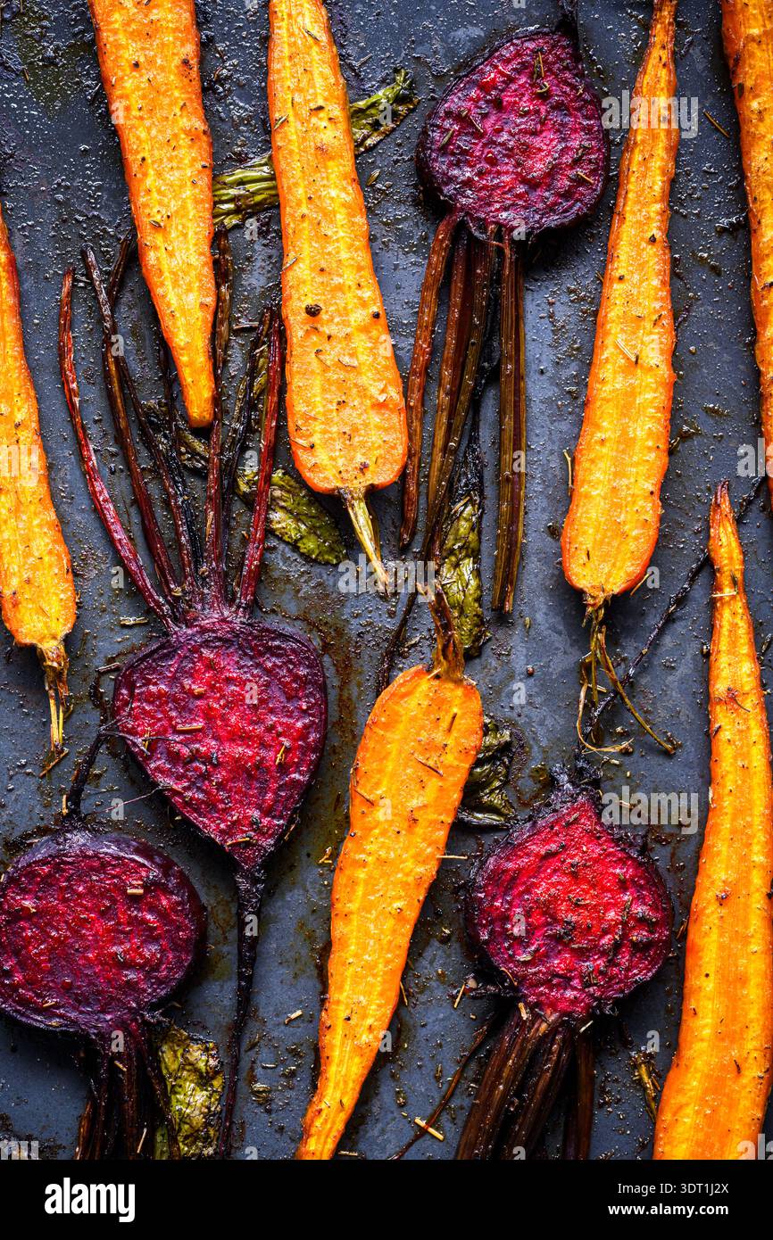 Roasted beetroot and carrots with spices on dark background. Baked vegetable food with rich texture Stock Photo