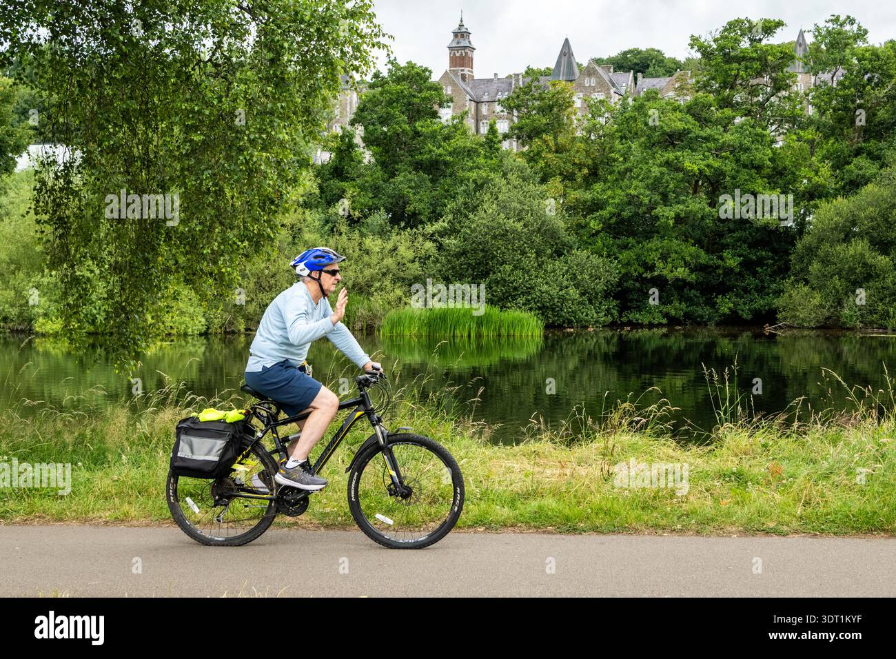 Man waving as he cycles along the Lee Fields on the River Lee, Cork, Ireland. Stock Photo