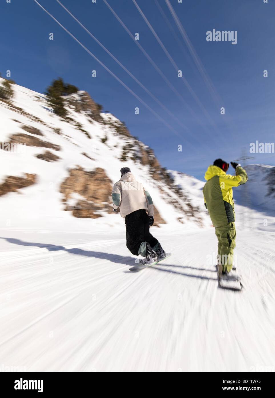 Snowboarders skillfully glide down a snowy mountain slope in the Pyrenees, capturing the excitement of winter sports. Bright sky and snow create a viv Stock Photo