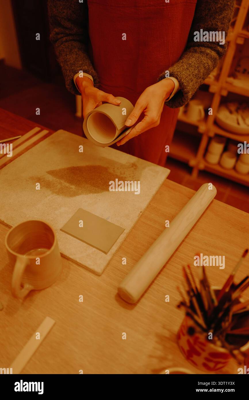 Young woman sculpting clay in pottery workshop Stock Photo