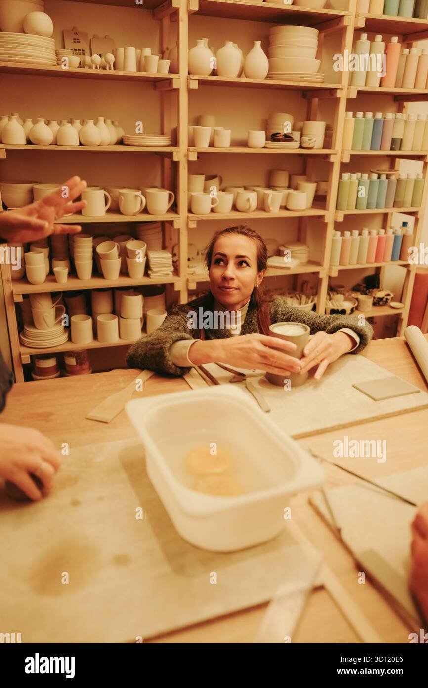 Young woman sculpting clay in pottery workshop Stock Photo