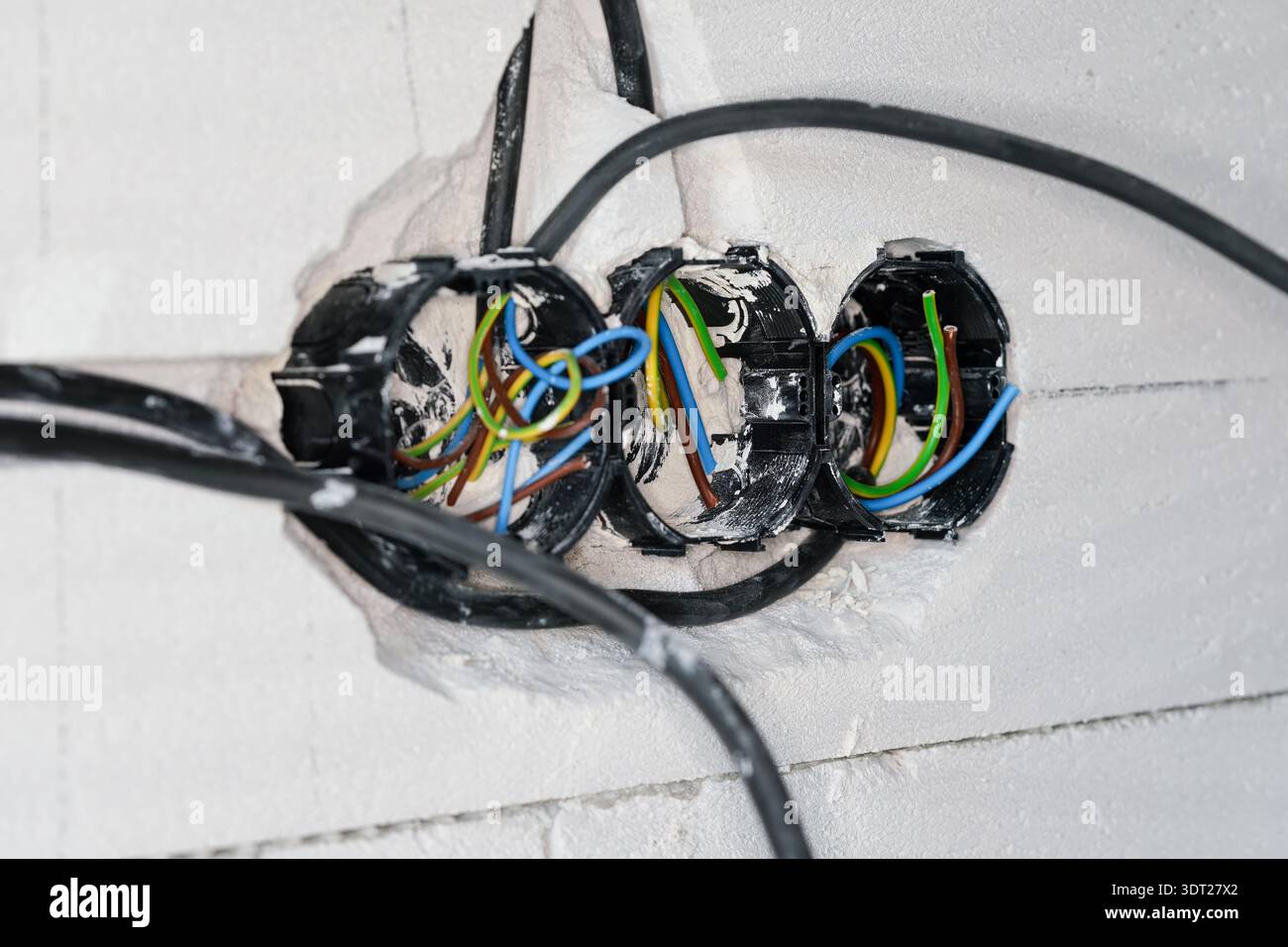 Boxes with cables for electric sockets installed in new house building empty wall Stock Photo