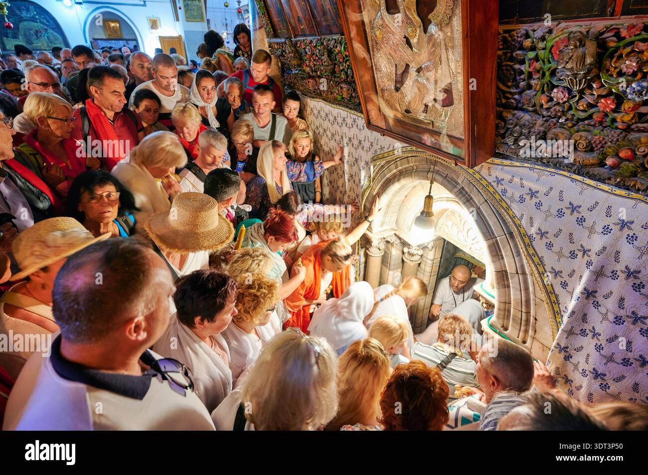 Many people are crowded together in the grotto of the nativity. They ...