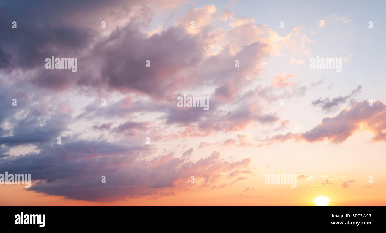 Dramatic clouds with sun rays breaking through sunset sky Stock Photo