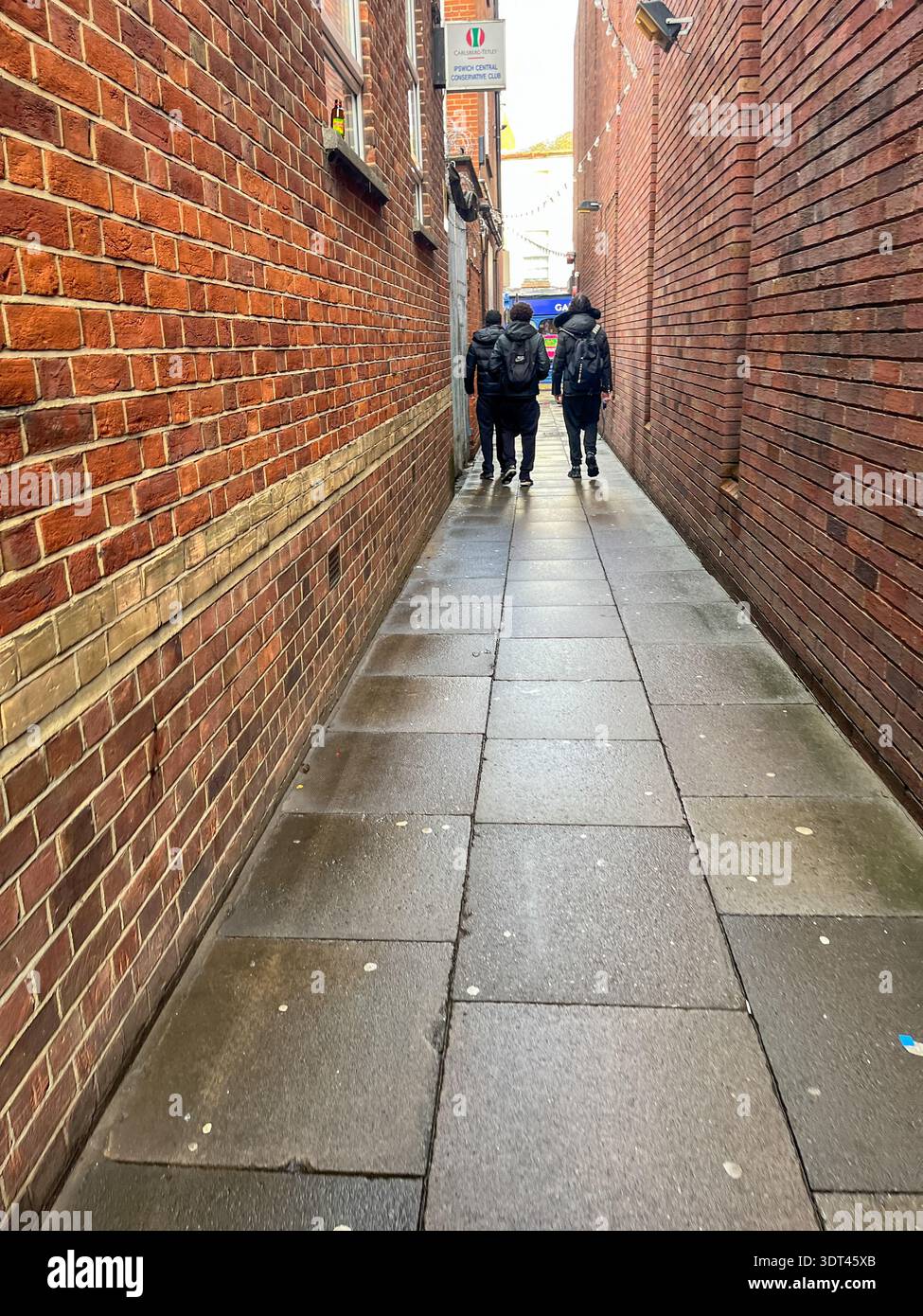 People walking through a narrow brick alleyway in Ipswich town centre, Suffolk, England, UK. - Smartphone Captured Stock Image