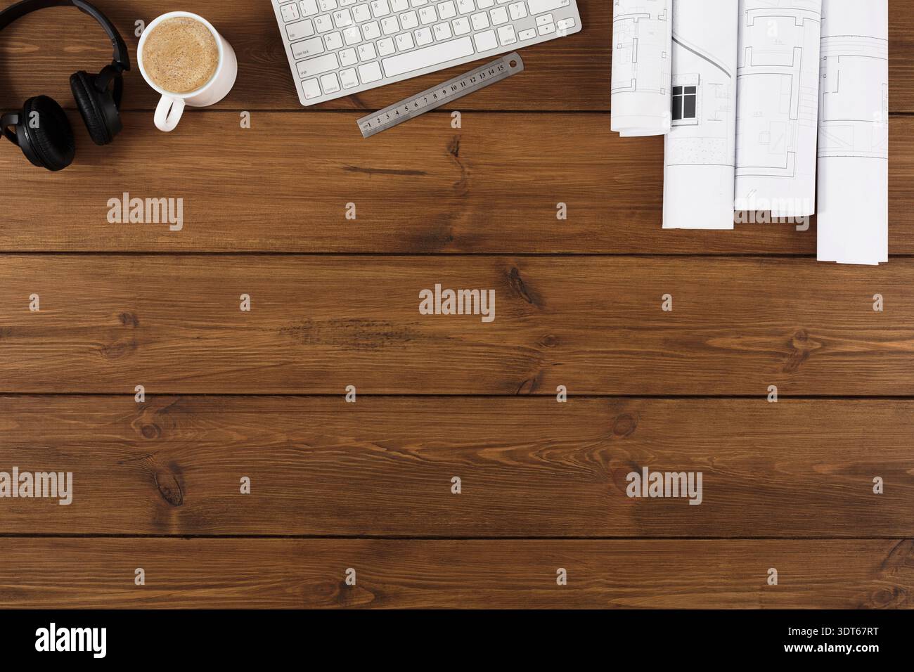 Workspace With Coffee, Keyboard, Headphones, and Architectural Plans on Wooden Table Stock Photo