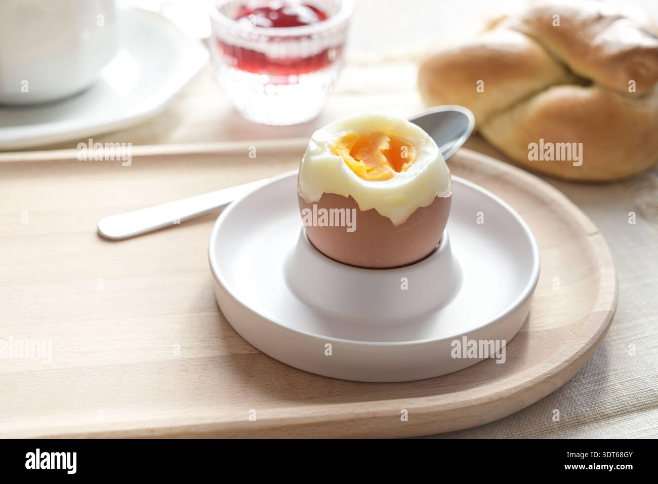 Opened boiled egg with soft yolk in an egg cup on a wooden plate, delicious protein for breakfast, brunch, or lunch, copy space, selected focus, narro Stock Photo
