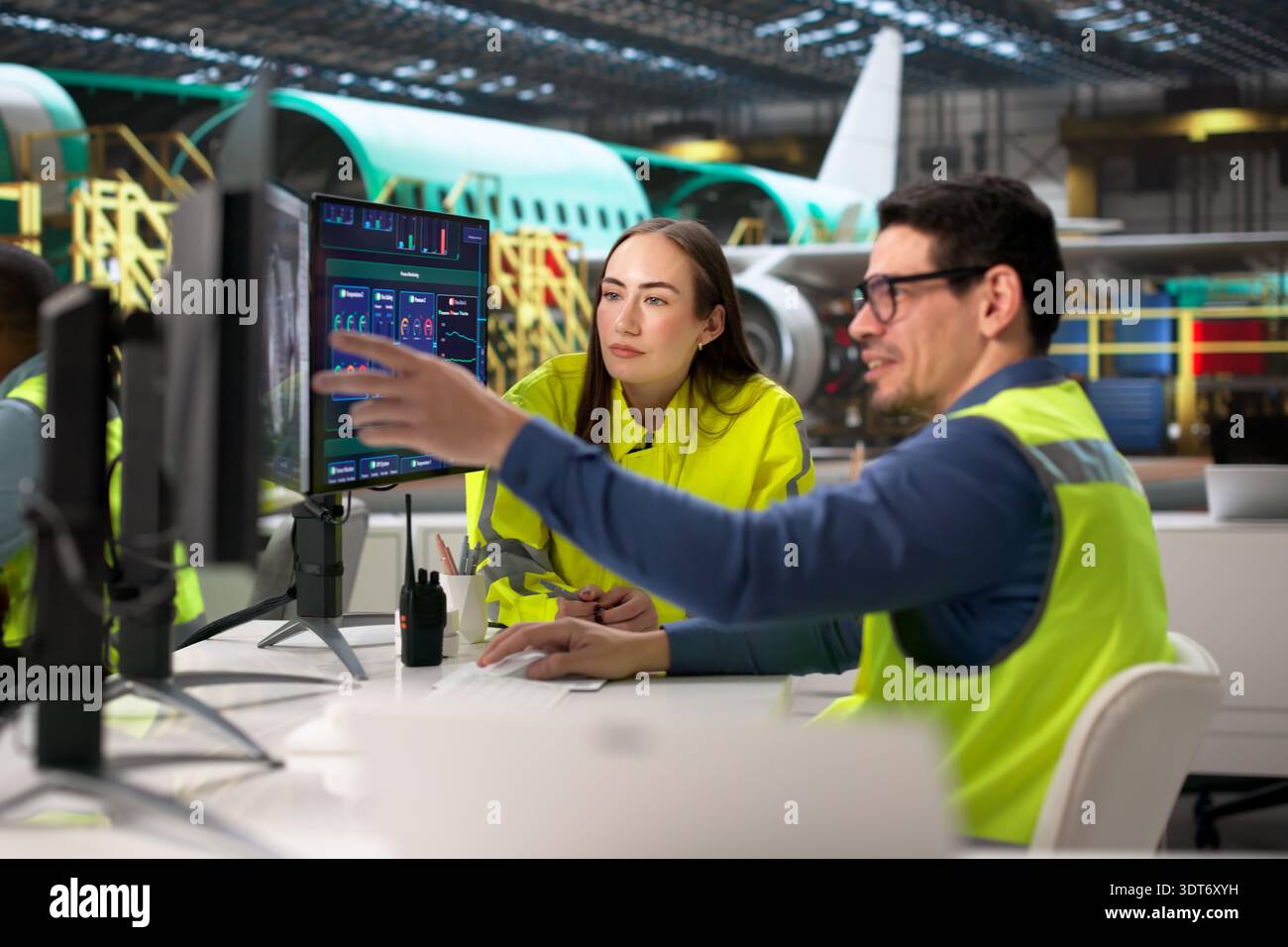 Engineers Utilizing CAD Models On Computer In Aerospace Manufacturing Facility. Stock Photo