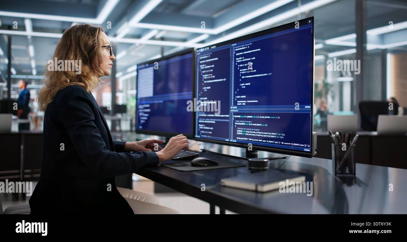 Female Programmer Developing Secure Software From Office Desk Using Computer Stock Photo
