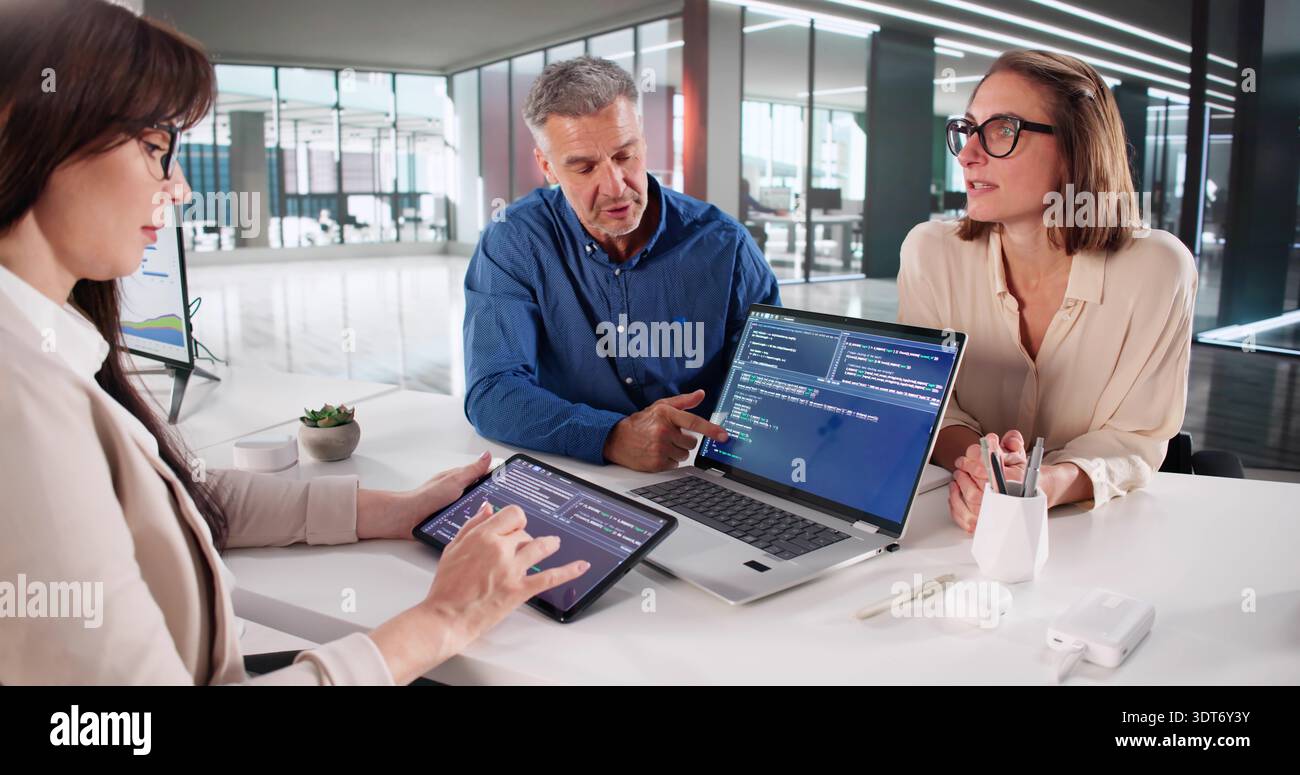 Business Team Meeting To Develop Software Code On Laptop And Tablets. Stock Photo
