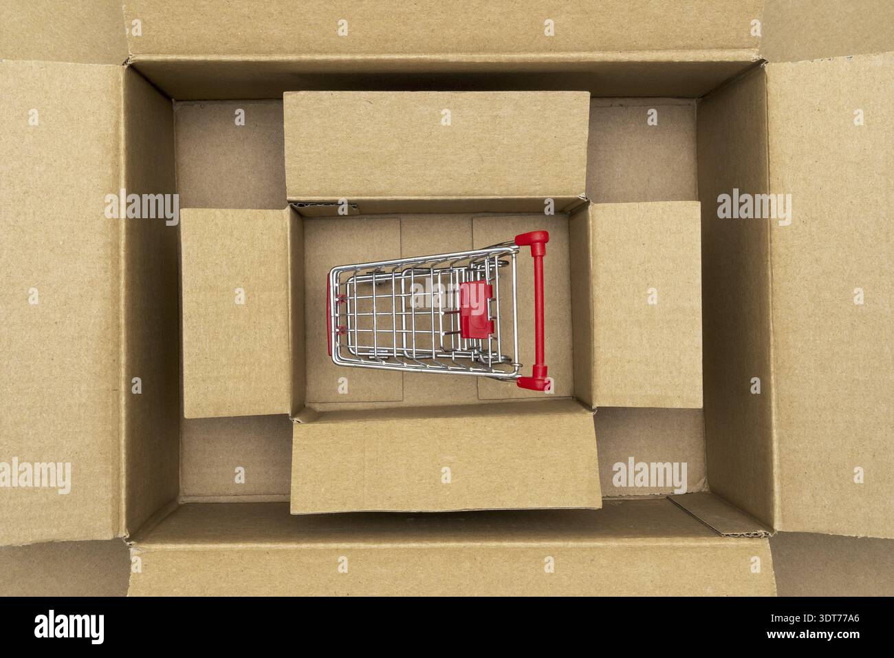 Shopping cart inside open rectangular cardboard box. Online internet shopping concept, e-commerce Stock Photo