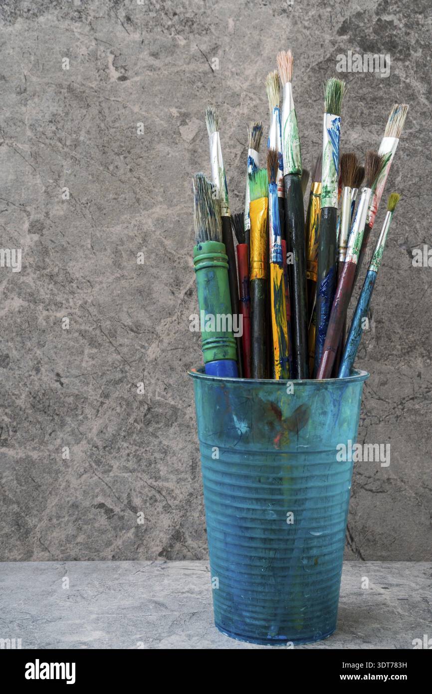 Dirty plastic flask with assorted painting brushes Stock Photo