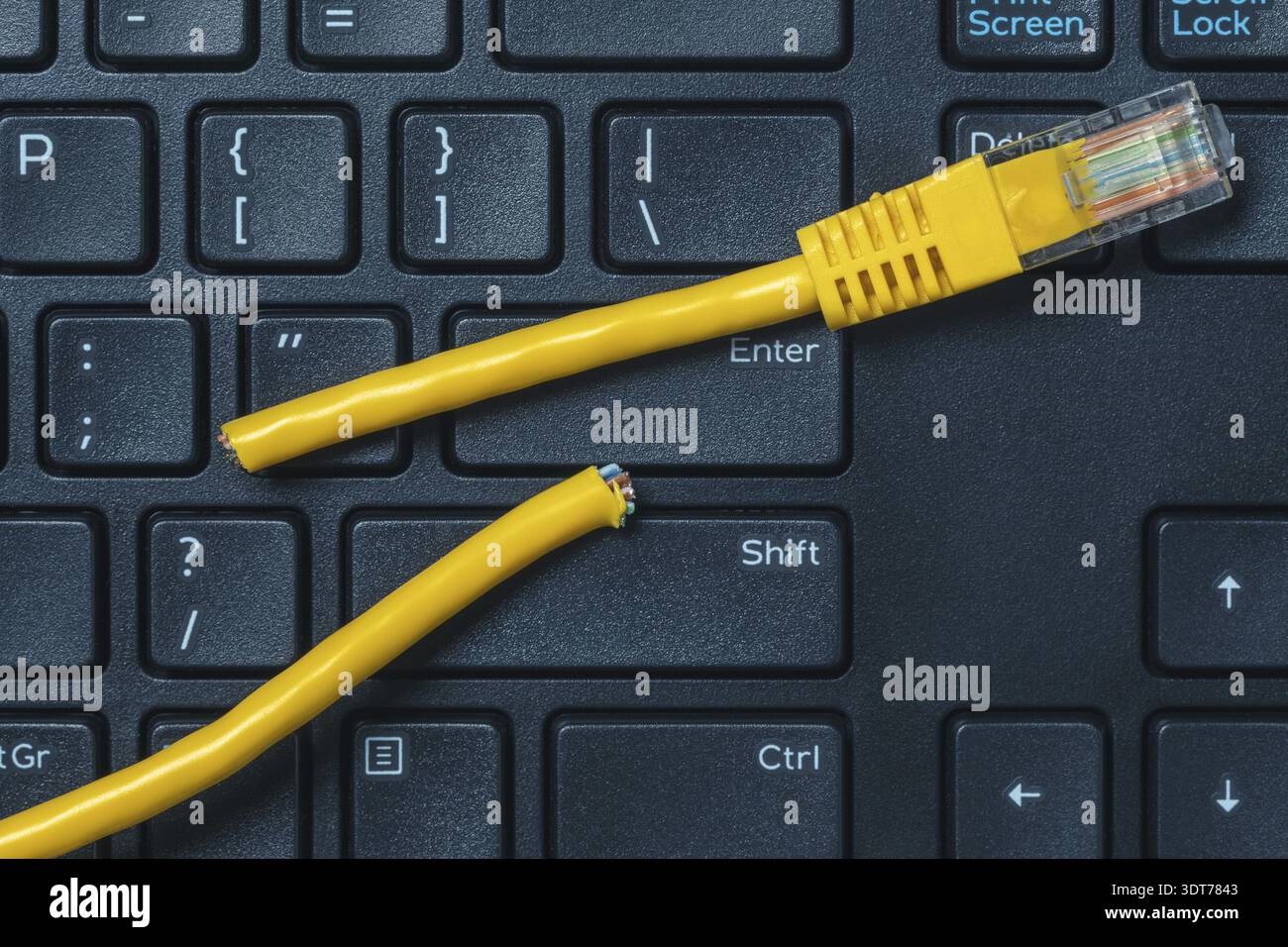 Internet connection disconnected. Computer keyboard with yellow network cable cutted off Stock Photo
