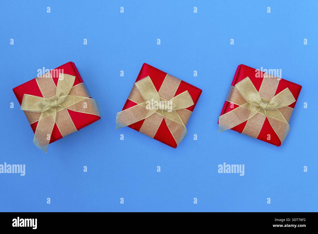Three Gift boxes with golden bows on blue background. Top view Stock Photo