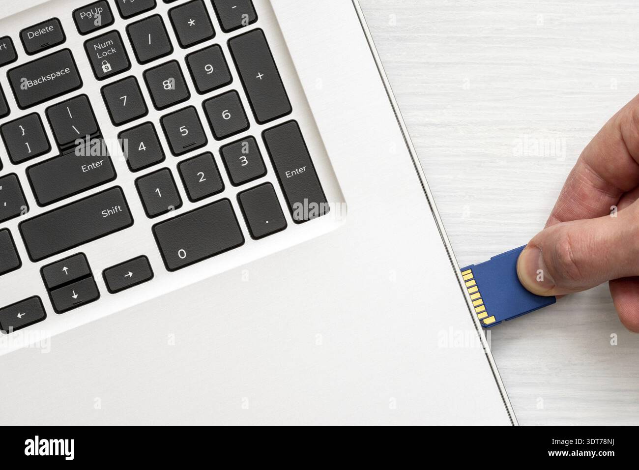 Hand inserting memory card into laptop slot Stock Photo