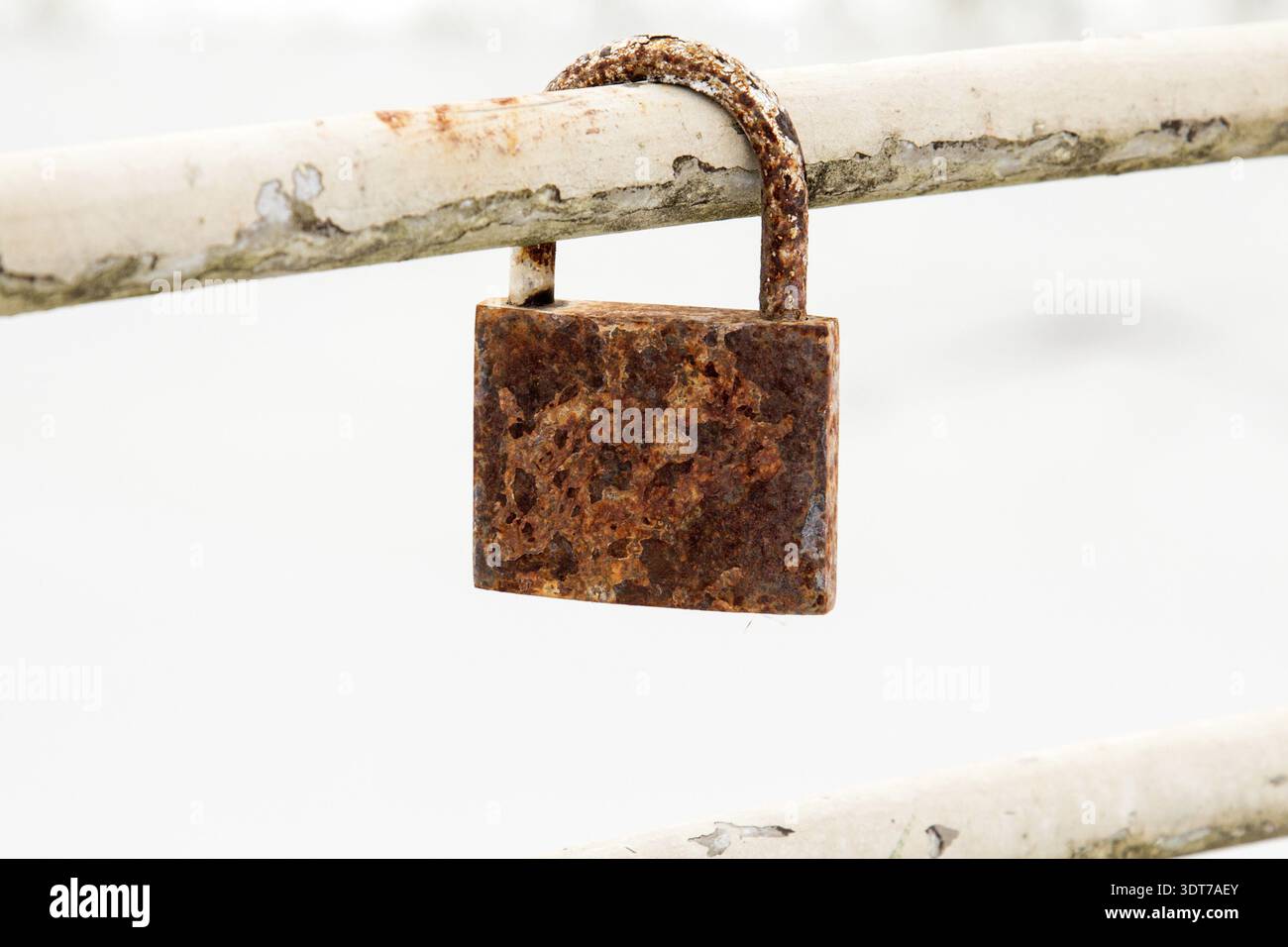 Old rusty padlock hanging on metal bar Stock Photo