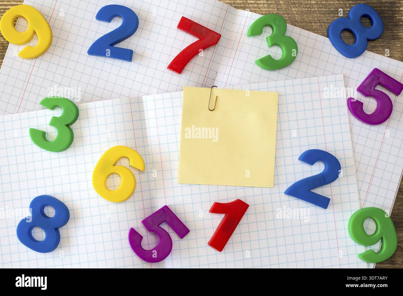 Squared exercise book with colored numbers and blank sticky note Stock Photo