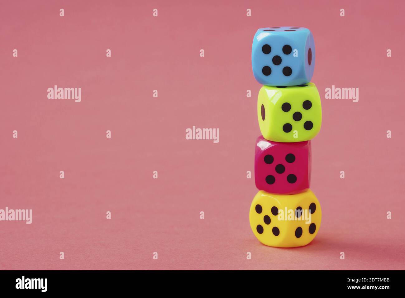 Stack of colorful dice on pink background. Copy space Stock Photo