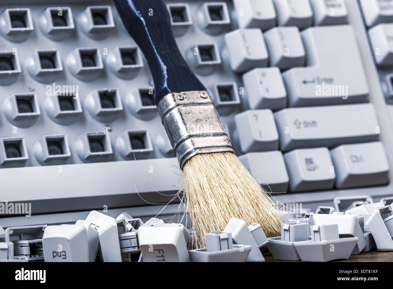 Brush on the old broken computer keyboard. Cleaning old keyboard Stock Photo