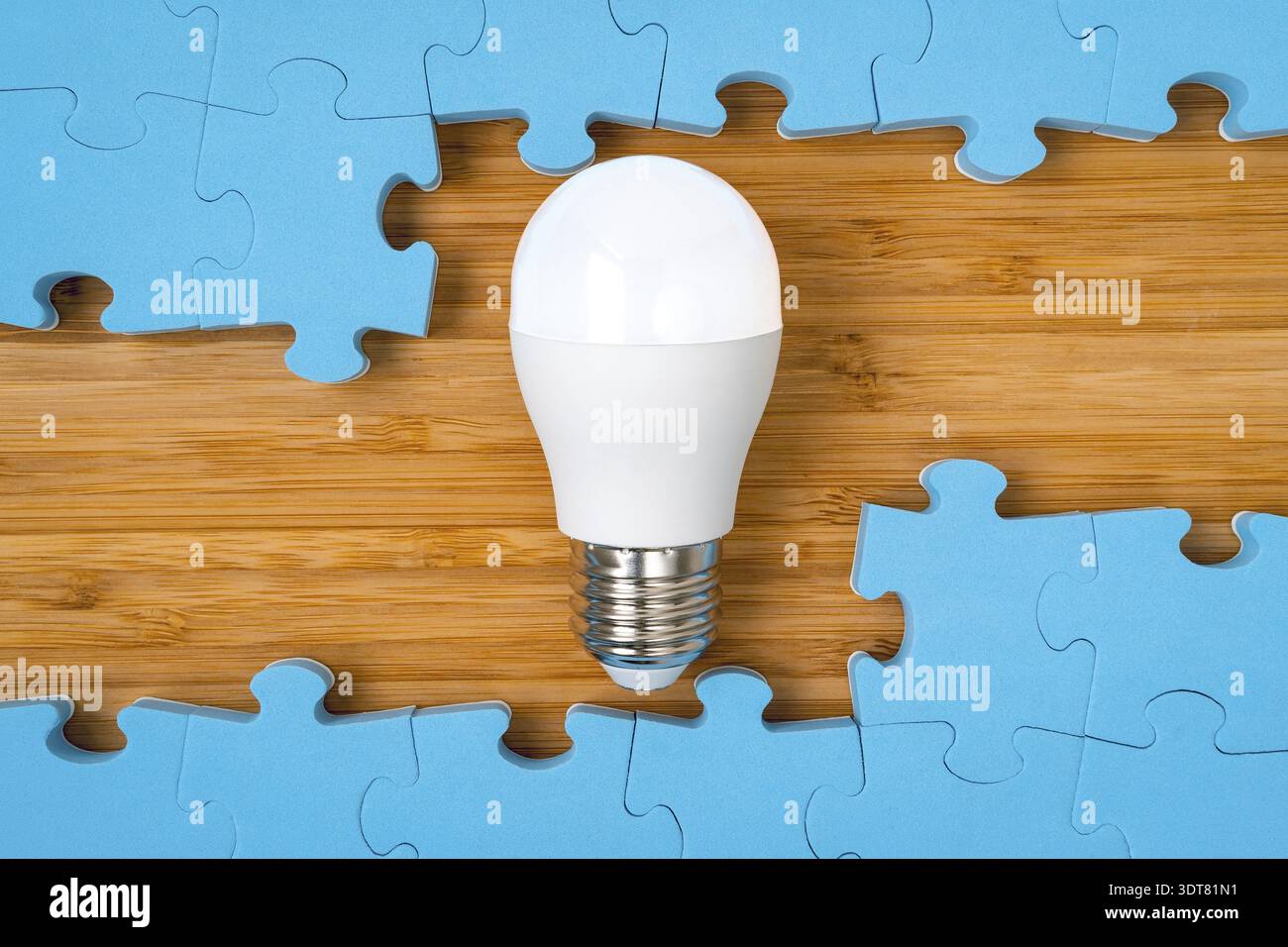 Blue puzzle frame with a bright light bulb in the middle. Concept for problem solving, solution strategy and idea Stock Photo