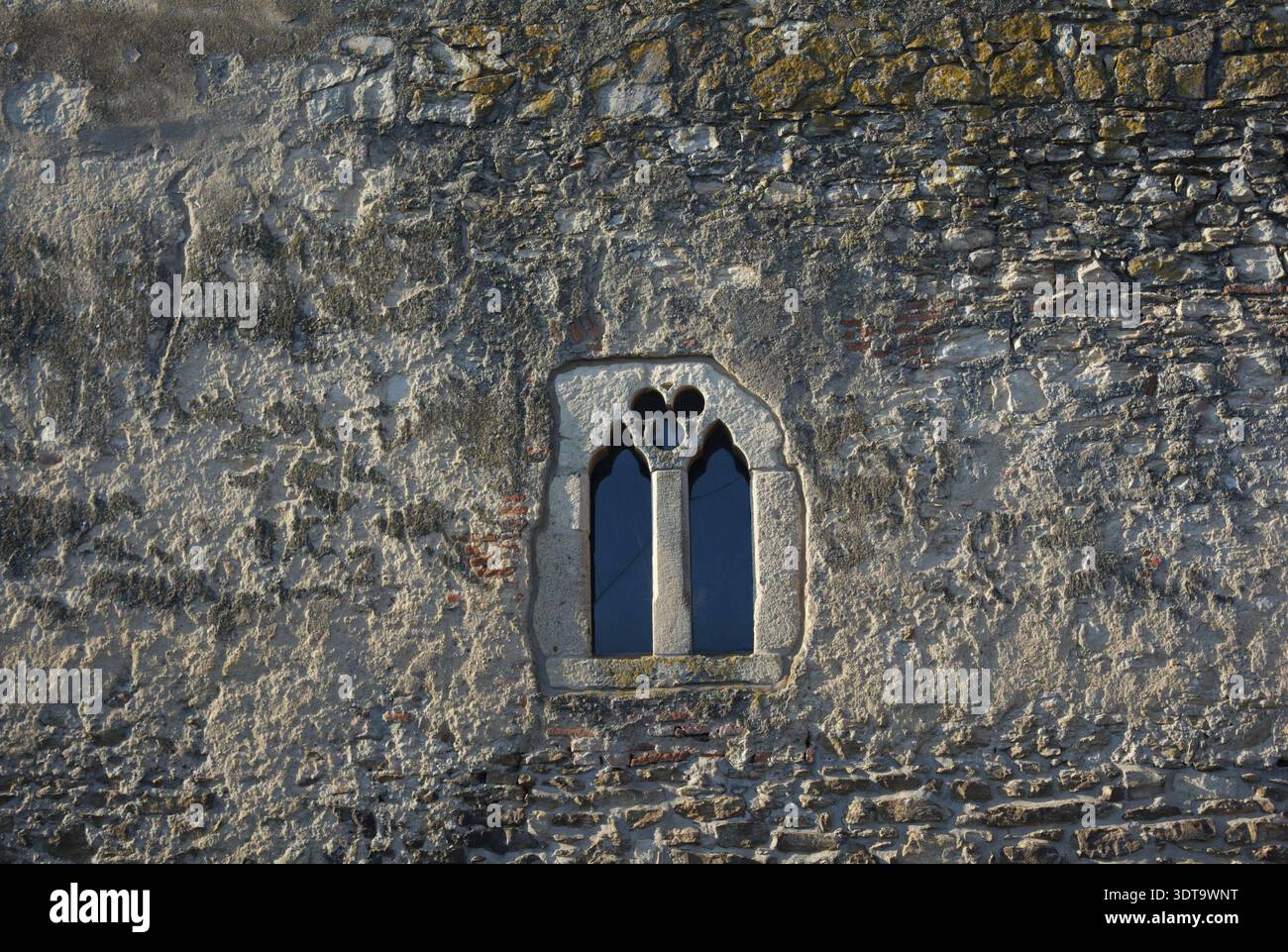 Small window on ancient stone wall Stock Photo